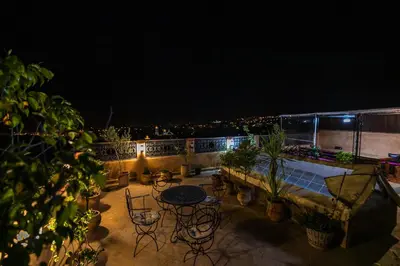 a rooftop patio with tables and chairs at night at Dar Naima in Fès