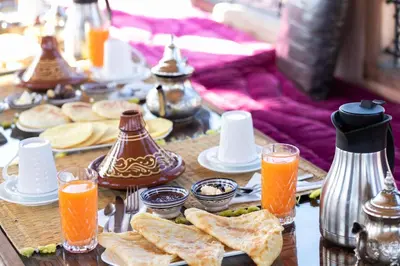 a table with plates of food and glasses of orange juice at Dar Naima in Fès