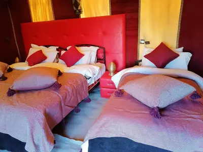 a bedroom with two beds with red headboards at Erg Merzouga Desert Camp in Merzouga