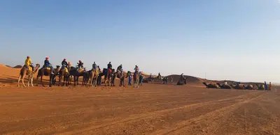 a group of people riding horses in the desert at Erg Merzouga Desert Camp in Merzouga
