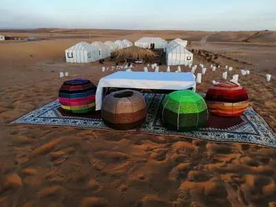 a group of colorful containers sitting on the desert at Erg Merzouga Desert Camp in Merzouga