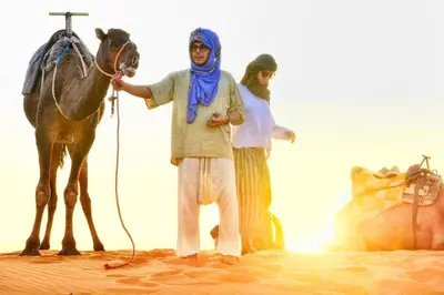 a man standing next to a horse in the desert at Erg Merzouga Desert Camp in Merzouga