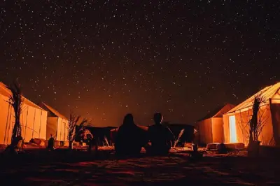 a group of people sitting under a starry sky at Erg Merzouga Desert Camp in Merzouga