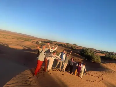 a group of people standing on a sand dune at Bivouac Luna in Mhamid