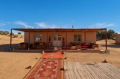 a house in the desert with a rug in front of it at Bivouac Luna in Mhamid