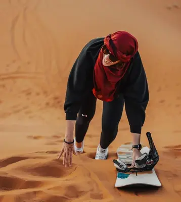 a woman bending over in the sand in the desert at Merzouga Berbers Luxury Camp in Merzouga