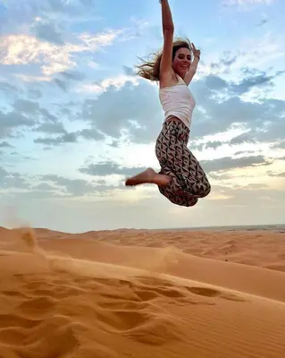 a woman jumping in the air in the desert at Merzouga Berbers Luxury Camp in Merzouga