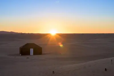 a barn in the desert with the sunset in the background at Authentique berber Camp & Activities in Mhamid