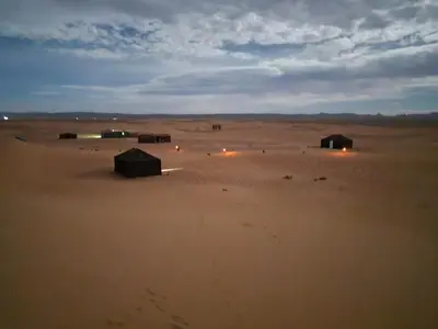 a group of huts in the middle of a desert at Authentique berber Camp & Activities in Mhamid