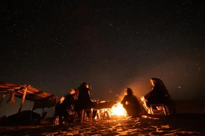 a group of people sitting around a fire on the beach at night at Authentique berber Camp & Activities in Mhamid
