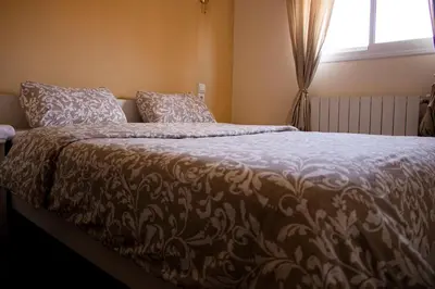 a bed with a brown and white blanket and a window at Un havre de paix à Ifrane in Ifrane