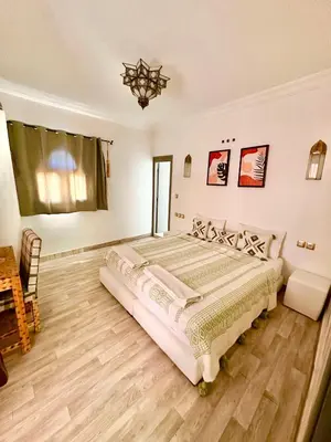 a bedroom with a large bed and a chandelier at Hotel Riad Amlal in Ouarzazate