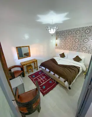 a bedroom with a bed and a chair and a mirror at Hotel Riad Amlal in Ouarzazate