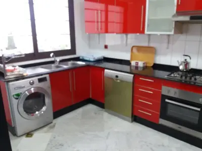 a kitchen with red cabinets and a washing machine at top Appartement in Fes City Marbella House in Fès