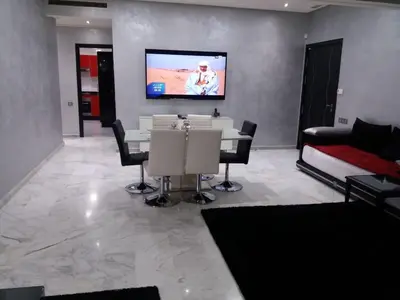 a living room with a table and a tv on a wall at top Appartement in Fes City Marbella House in Fès