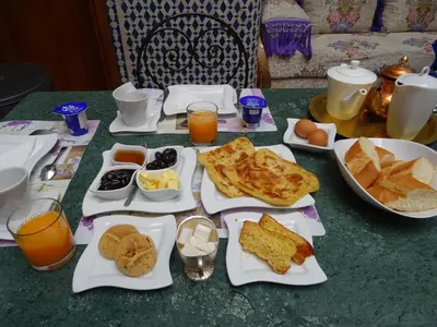 a table topped with plates of breakfast foods and orange juice at Dar Al Safadi in Fès
