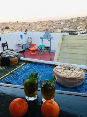 a table with two glasses and oranges on a balcony at Moroccan Dream Hostel in Fès