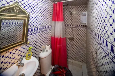 a bathroom with a sink and a red shower curtain at Dar Lalla Bouchra in Fès