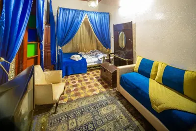 a bedroom with a bed and blue curtains and a couch at Dar Lalla Bouchra in Fès