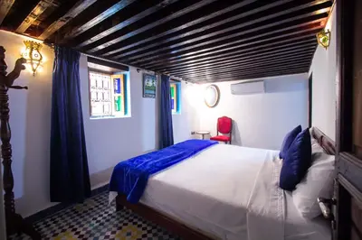 a bedroom with a bed with blue and white sheets at Dar Alami Salaj in Fès