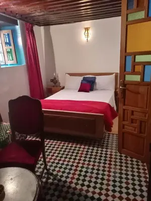 a bedroom with a bed and a chair and a door at Dar Alami Salaj in Fès