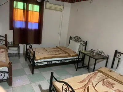 a room with two beds and a table with a window at Bab Al Madina in Fès