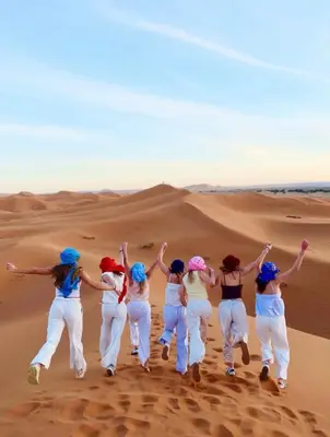 a group of women jumping in the desert at Sahara Bedouins Camp in Hassilabied
