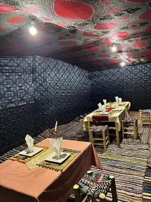 a dining room with two tables and a patterned wall at Sahara Bedouins Camp in Hassilabied