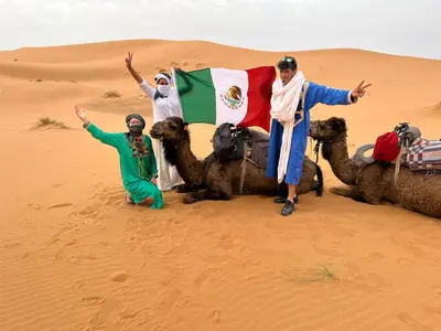 a group of people with their camels in the desert at Sahara Bedouins Camp in Hassilabied