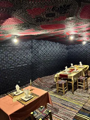 a dining room with two tables and a patterned wall at Sahara Bedouins Camp in Hassilabied