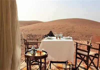 a table and chairs in the middle of the desert at Camel Trekking Desert Camp in Merzouga