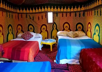 a room with two beds with faces painted on the wall at Camel Trekking Desert Camp in Merzouga