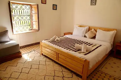 a bedroom with a large wooden bed with a window at Dar Ait Bouguemez in Azilal