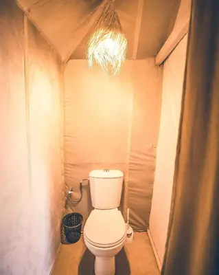 a bathroom with a toilet in a small room at Blue Sky Luxury Camp in Merzouga