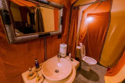 a bathroom with a sink and a toilet and a mirror at Blue Sky Luxury Camp in Merzouga