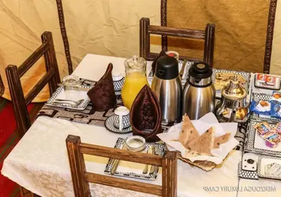 a table with a white table cloth with food and drinks at Blue Sky Luxury Camp in Merzouga