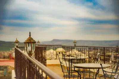 a patio with tables and chairs on a balcony at Le Grand Alcazar - Riad in Fès