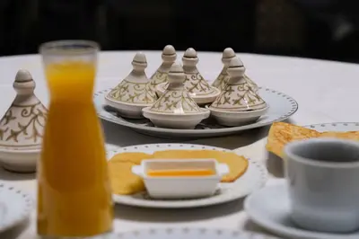 a table with plates of food and a glass of orange juice at Le Grand Alcazar - Riad in Fès