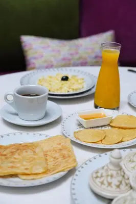a table with plates of food and a cup of coffee at Le Grand Alcazar - Riad in Fès