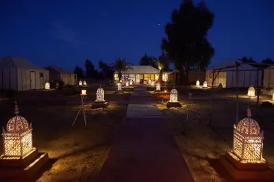 a group of cages with lights in a field at night at glamping Dunes CAMP in Merzouga