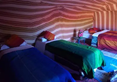 a room with two beds and a colorful wall at glamping Dunes CAMP in Merzouga