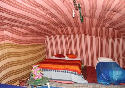 a bedroom with a bed in a room with stripes at glamping Dunes CAMP in Merzouga