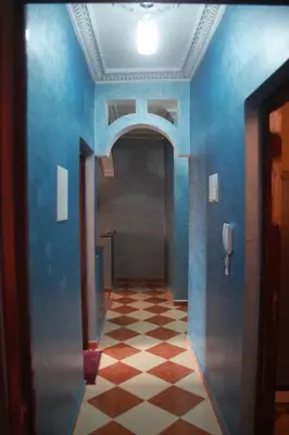 a hallway with blue walls and a checkered floor at Résidence dikre in Ouarzazate