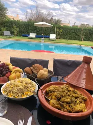 a table topped with plates of food next to a pool at fleur de marrakech in Marrakech