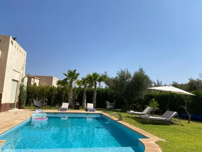 a swimming pool in a yard with chairs and an umbrella at fleur de marrakech in Marrakech
