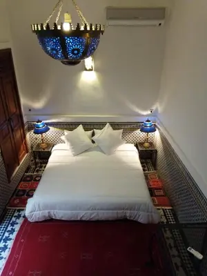 a bedroom with a white bed with a chandelier at Dar Abdesalam in Fès