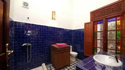 a blue tiled bathroom with a toilet and a sink at Dar Abdesalam in Fès