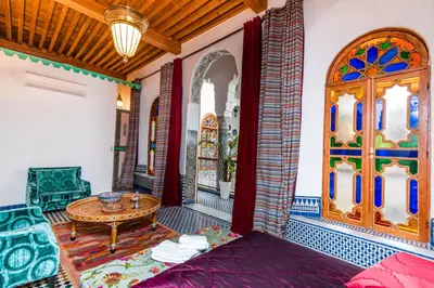 a living room with a table and a door at Riad Fes Nass Zmane in Fès
