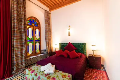 a bedroom with a bed and a stained glass window at Riad Fes Nass Zmane in Fès