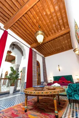 a living room with a table in the middle of a room at Riad Fes Nass Zmane in Fès